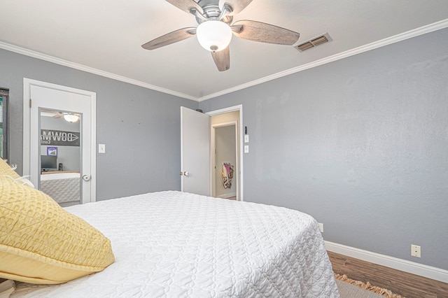 bedroom with visible vents, ornamental molding, ceiling fan, wood finished floors, and baseboards