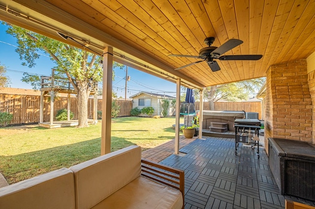 exterior space with a fenced backyard, a ceiling fan, and a hot tub