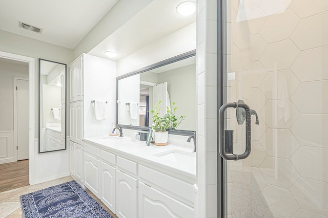 bathroom with double vanity, a stall shower, a sink, and visible vents