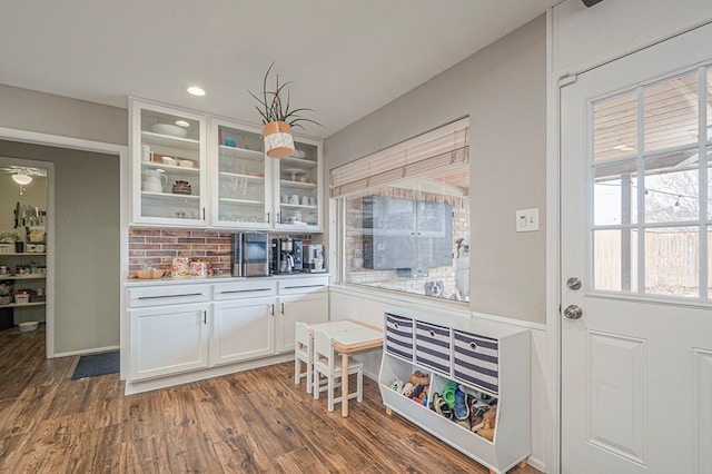 kitchen with dark wood finished floors, tasteful backsplash, recessed lighting, glass insert cabinets, and white cabinetry