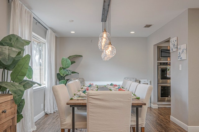 dining room featuring dark wood-type flooring, a wealth of natural light, and visible vents