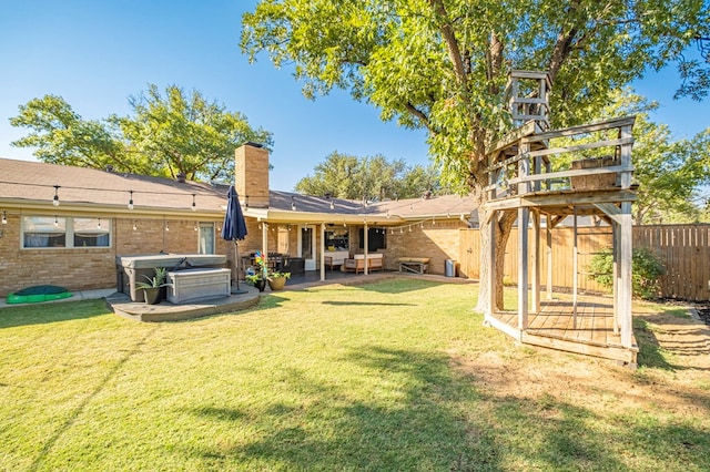 back of property with brick siding, a lawn, a chimney, and fence