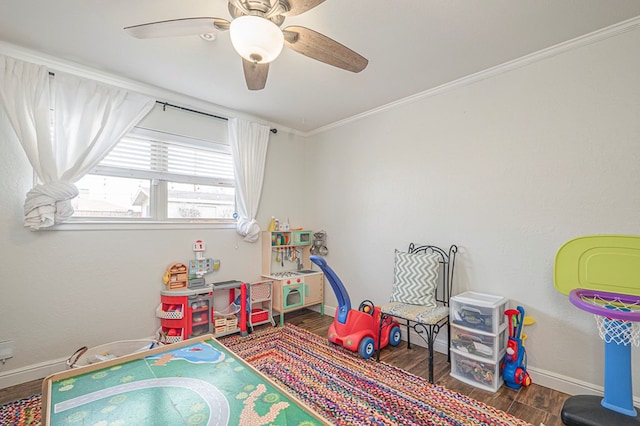 recreation room featuring dark wood-style flooring, crown molding, baseboards, and ceiling fan