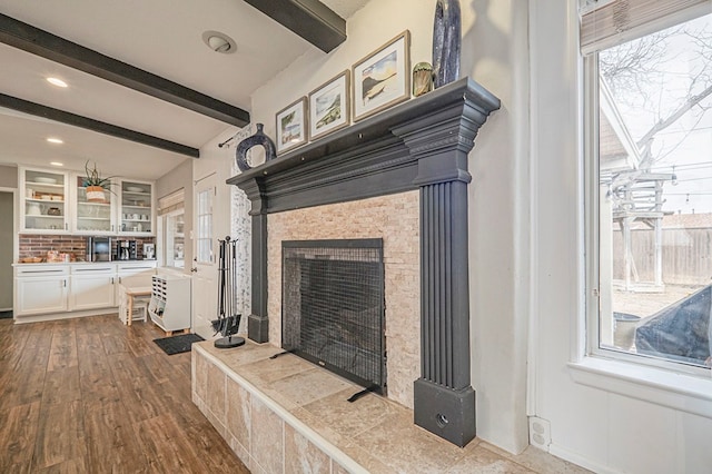 interior space with beamed ceiling, wood finished floors, and a tile fireplace