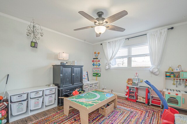 playroom with ornamental molding, ceiling fan, baseboards, and wood finished floors