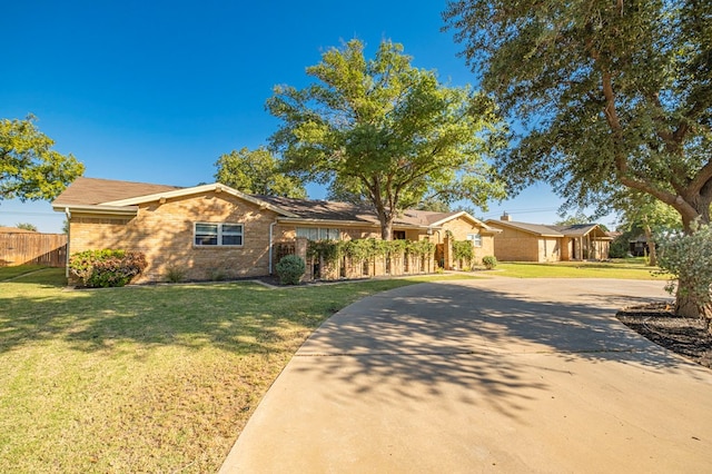 single story home with driveway, brick siding, a front lawn, and fence