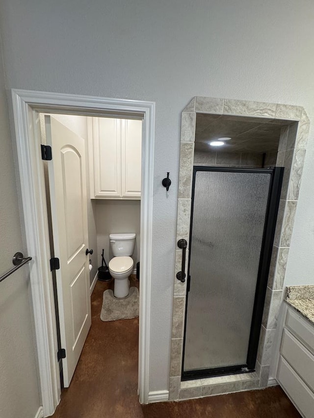 bathroom featuring vanity, toilet, and a shower with door