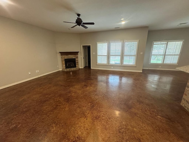 unfurnished living room featuring ceiling fan and a stone fireplace