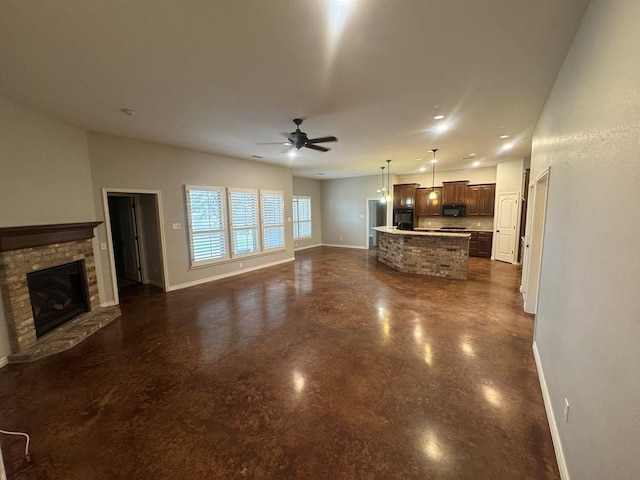 unfurnished living room featuring a stone fireplace and ceiling fan