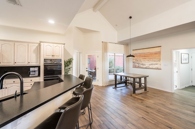 kitchen featuring hanging light fixtures, dark hardwood / wood-style flooring, sink, beam ceiling, and high vaulted ceiling