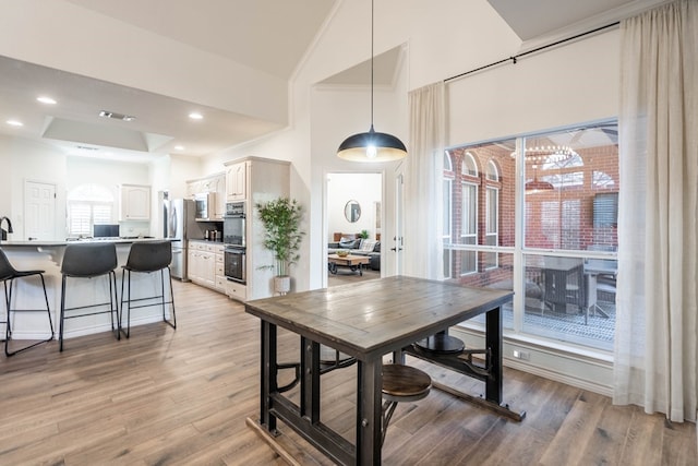 dining area featuring lofted ceiling and light wood-type flooring