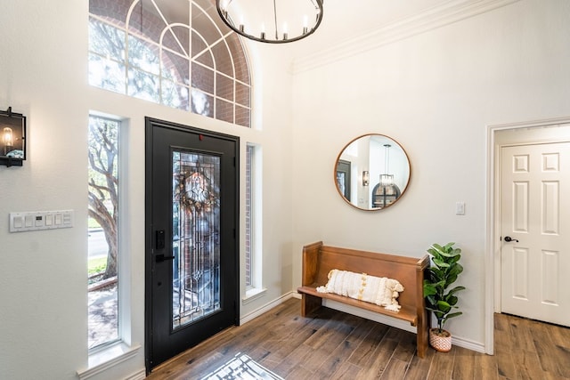 entrance foyer with a notable chandelier, crown molding, and wood-type flooring