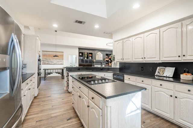 kitchen featuring black appliances, light hardwood / wood-style floors, hanging light fixtures, sink, and backsplash