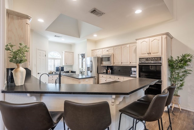 kitchen with stainless steel appliances, decorative backsplash, kitchen peninsula, and dark hardwood / wood-style flooring