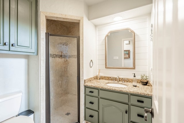 bathroom featuring toilet, a shower with shower door, and vanity