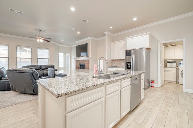 kitchen featuring sink, a kitchen island with sink, ceiling fan, light stone counters, and stainless steel dishwasher