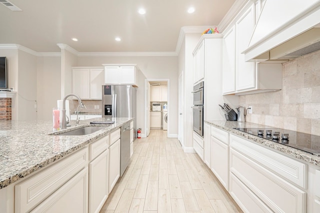 kitchen with custom exhaust hood, appliances with stainless steel finishes, light stone countertops, ornamental molding, and sink