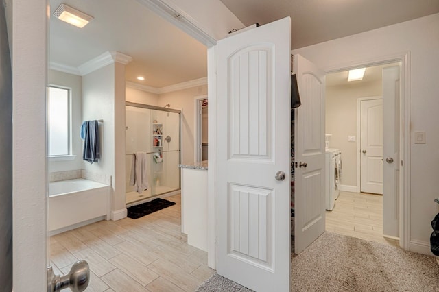 bathroom featuring washing machine and dryer, plus walk in shower, and ornamental molding