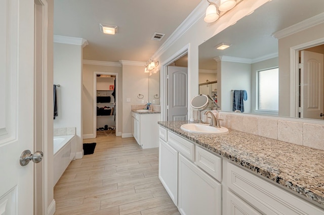 bathroom with a tub, crown molding, and vanity