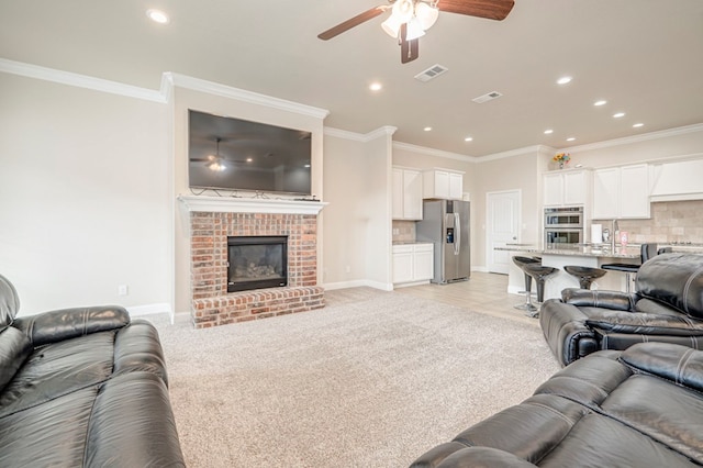 carpeted living room featuring ceiling fan, sink, ornamental molding, and a fireplace