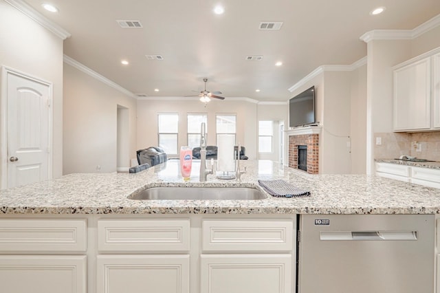 kitchen with ceiling fan, a brick fireplace, dishwasher, ornamental molding, and light stone counters