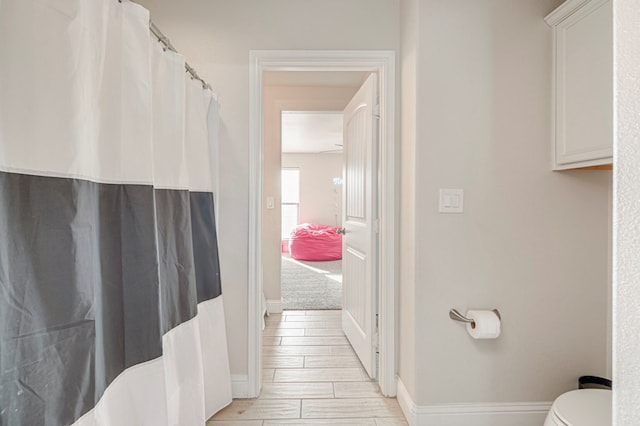 bathroom with curtained shower, toilet, and baseboards