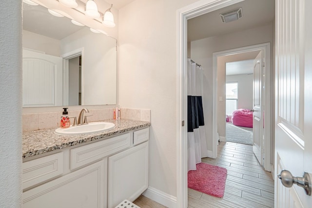 full bath featuring wood finish floors, visible vents, vanity, and baseboards