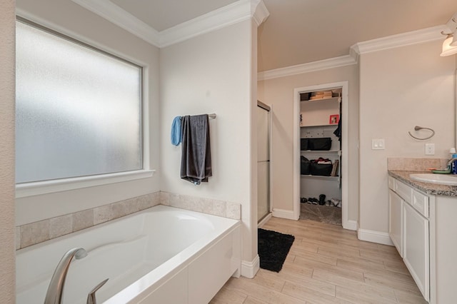 bathroom with vanity, a garden tub, ornamental molding, wood finished floors, and a spacious closet