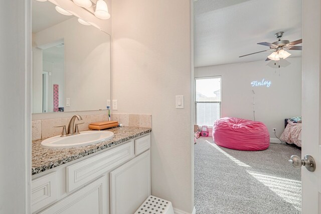 bathroom featuring vanity, a ceiling fan, ensuite bathroom, and baseboards