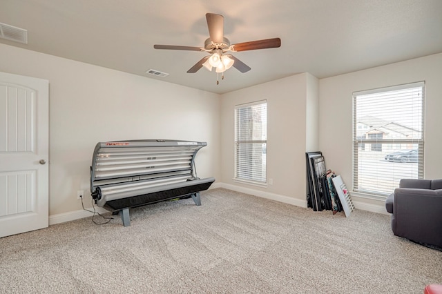 interior space featuring baseboards, visible vents, ceiling fan, and carpet flooring