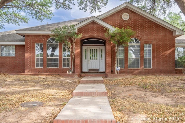 view of front of home featuring brick siding and a shingled roof
