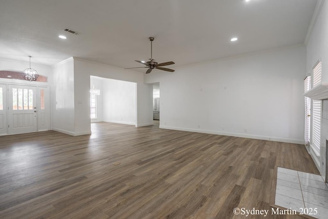 unfurnished living room featuring ceiling fan, a chandelier, crown molding, wood finished floors, and baseboards