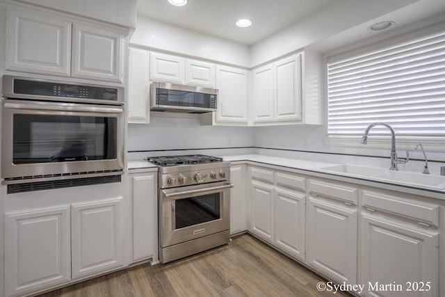 kitchen featuring appliances with stainless steel finishes, a sink, white cabinetry, and recessed lighting