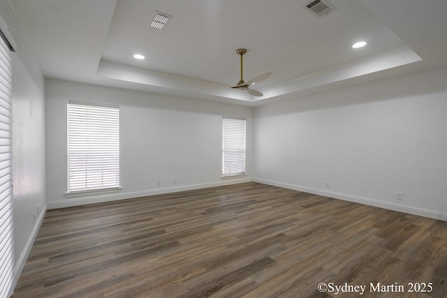 empty room featuring a raised ceiling, a ceiling fan, dark wood-style floors, baseboards, and recessed lighting