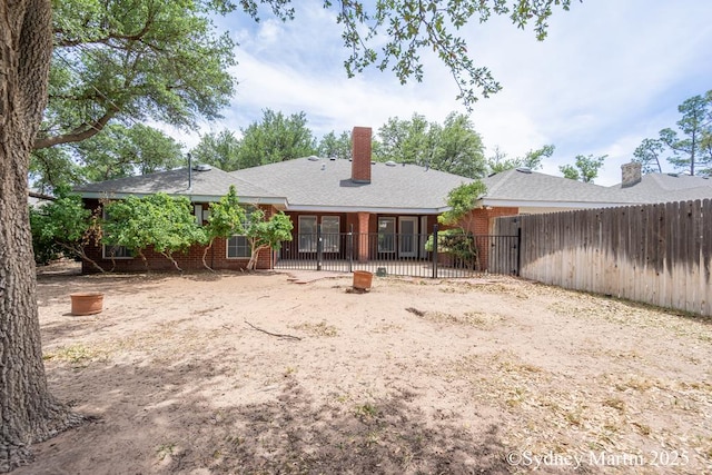 back of house featuring fence, brick siding, and a chimney