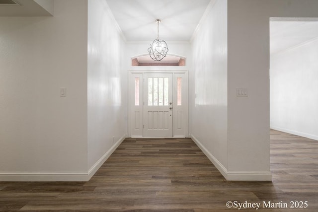 entrance foyer featuring ornamental molding, dark wood-style floors, baseboards, and a chandelier