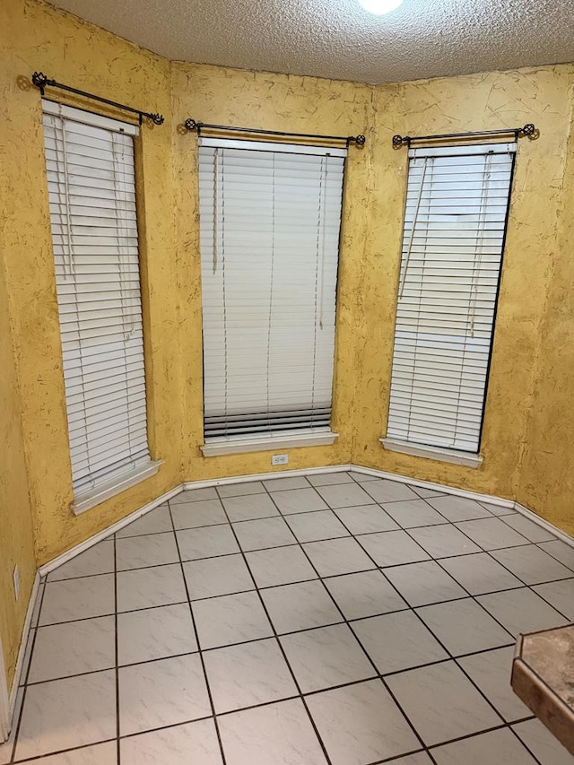 empty room with tile patterned flooring and a textured ceiling