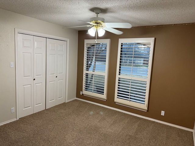 unfurnished bedroom with ceiling fan, a closet, a textured ceiling, and carpet