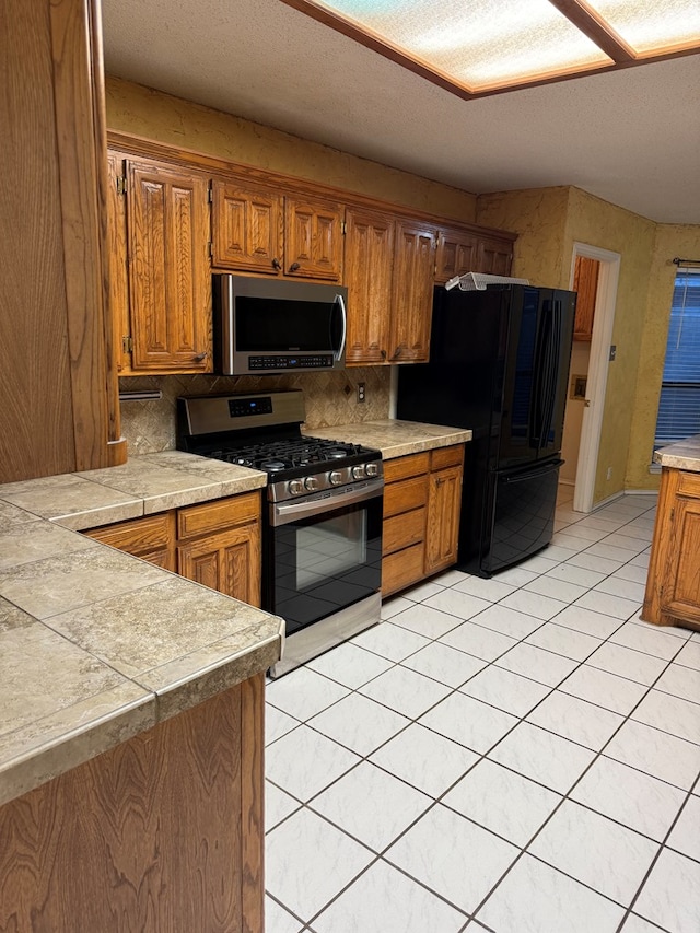 kitchen with appliances with stainless steel finishes, light tile patterned floors, and backsplash