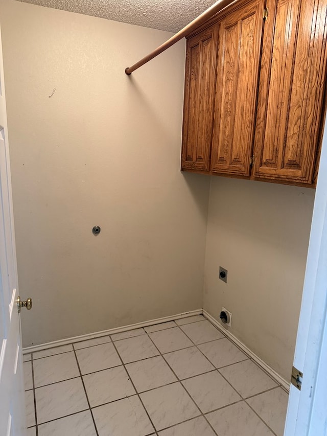 laundry room with cabinets, light tile patterned flooring, hookup for an electric dryer, and a textured ceiling