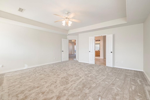 empty room with ceiling fan, carpet, and a tray ceiling