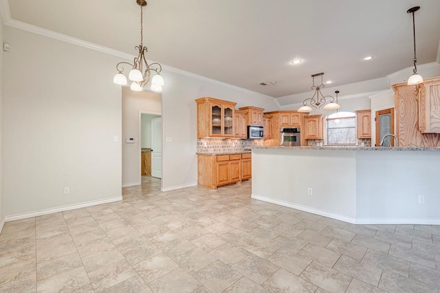 kitchen with appliances with stainless steel finishes, tasteful backsplash, light stone countertops, a chandelier, and crown molding