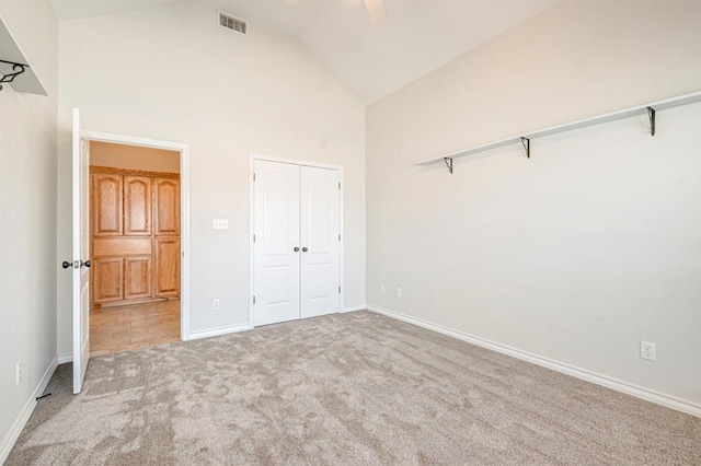 unfurnished bedroom featuring light carpet, a closet, high vaulted ceiling, and ceiling fan