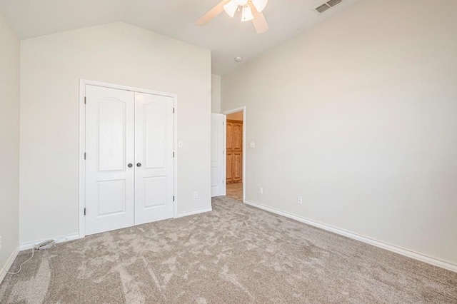 unfurnished bedroom featuring ceiling fan, light carpet, a closet, and lofted ceiling