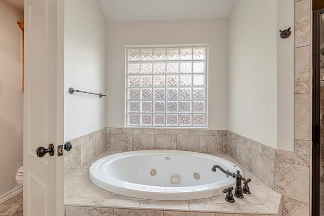 bathroom featuring tiled bath and toilet