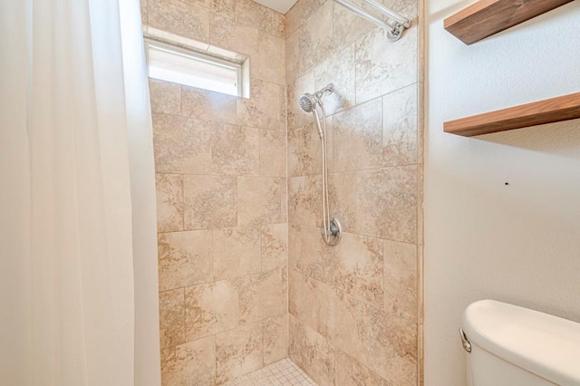 bathroom with toilet and a tile shower