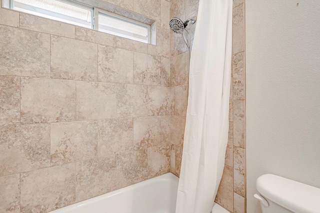 bathroom featuring toilet and shower / tub combo with curtain