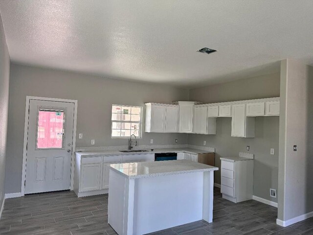 kitchen featuring a center island, sink, dark hardwood / wood-style floors, a textured ceiling, and white cabinets