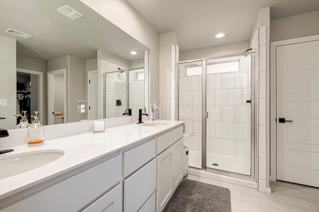 full bathroom with double vanity, a stall shower, a sink, and visible vents