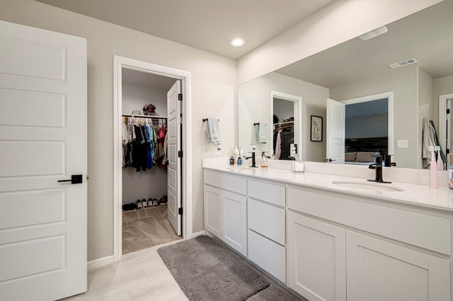 bathroom with double vanity, visible vents, a sink, and recessed lighting